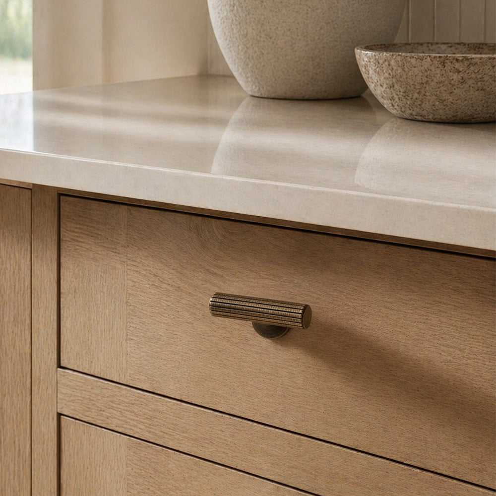 Reeded solid brass t-bar handle in antique brass finish on a modern kitchen drawer